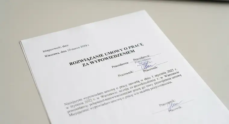 Dokument wypowiedzenia umowy o pracę na biurku obok kalendarza i długopisu, co ilustruje początek okresu wypowiedzenia
